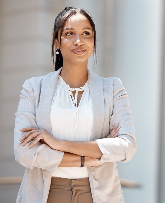 A healthcare operations professional in a light blazer, arms crossed, looking aside