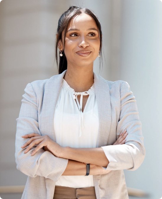 A healthcare administrator in a light blazer standing with her arms crossed